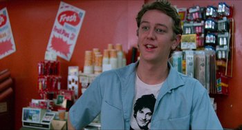 Movie still from “Fast Times at Ridgemont High” (1982), directed by Amy Heckerling – A young man in a blue shirt is standing in front of a counter; Medium shot, Over the shoulder angle