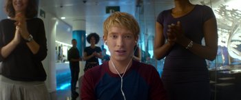 Movie still from “Ex Machina” (2014), directed by Alex Garland – A young man with blonde hair and a red and blue shirt is listening to music; Close Up shot, Over the shoulder angle