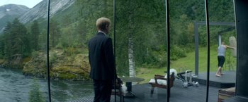 Movie still from “Ex Machina” (2014), directed by Alex Garland – A man in a suit standing in front of a window; Wide shot, Over the shoulder angle