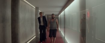 Movie still from “Ex Machina” (2014), directed by Alex Garland – A man and a woman walking down a hall way; Wide shot, Low angle