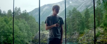 Movie still from “Ex Machina” (2014), directed by Alex Garland – A young man holding a beer in his hand; Medium shot, Low angle