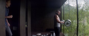 Movie still from “Ex Machina” (2014), directed by Alex Garland – A man standing in front of a window in a dark room; Medium shot, Low angle