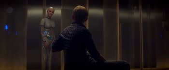 Movie still from “Ex Machina” (2014), directed by Alex Garland – A man sitting in front of a woman in front of a mirror; Medium shot, Over the shoulder angle