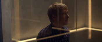 Movie still from “Ex Machina” (2014), directed by Alex Garland – A young man looking out of a window at night; Close Up shot, Over the shoulder angle