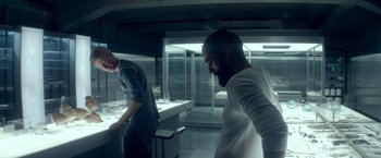 Movie still from “Ex Machina” (2014), directed by Alex Garland – Two men are standing in a kitchen looking at a counter; Medium shot, Low angle