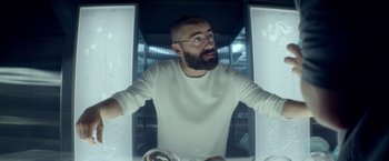 Movie still from “Ex Machina” (2014), directed by Alex Garland – A man with a goatee and glasses in a room; Medium shot, Low angle