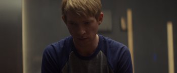 Movie still from “Ex Machina” (2014), directed by Alex Garland – A man with blonde hair and a blue and white raglan t - shirt; Close Up shot, Over the shoulder angle