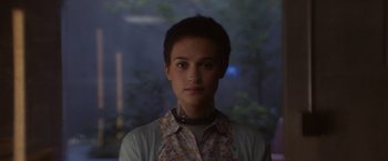 Movie still from “Ex Machina” (2014), directed by Alex Garland – A woman with short black hair wearing a floral shirt; Close Up shot, Over the shoulder angle