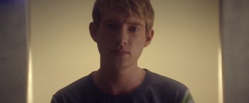 Movie still from “Ex Machina” (2014), directed by Alex Garland – A young man with blonde hair is looking at the camera; Close Up shot, Low angle