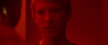Movie still from “Ex Machina” (2014), directed by Alex Garland – A young man in a red room looking at the camera; Close Up shot, Overhead angle
