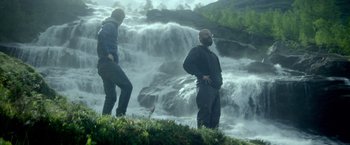 Movie still from “Ex Machina” (2014), directed by Alex Garland – Two men standing next to each other in front of a body of water; Wide shot, Low angle