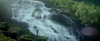 Movie still from “Ex Machina” (2014), directed by Alex Garland – A person standing in front of a large waterfall; Extreme Wide shot, Low angle