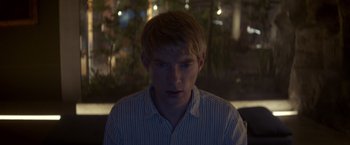 Movie still from “Ex Machina” (2014), directed by Alex Garland – A young man with blonde hair wearing a striped shirt; Close Up shot, Over the shoulder angle