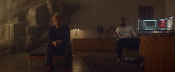 Movie still from “Ex Machina” (2014), directed by Alex Garland – Two people sitting in a room with a rug; Wide shot, Over the shoulder angle