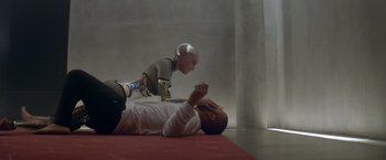 Movie still from “Ex Machina” (2014), directed by Alex Garland – A man laying on the ground next to a robot; Wide shot, High angle