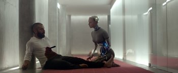 Movie still from “Ex Machina” (2014), directed by Alex Garland – A woman sitting on the ground next to a man; Wide shot, High angle
