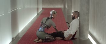 Movie still from “Ex Machina” (2014), directed by Alex Garland – A woman sitting on the ground next to a man; Wide shot, High angle
