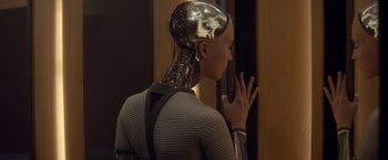 Movie still from “Ex Machina” (2014), directed by Alex Garland – A woman in a black and white dress with a robot head; Close Up shot, Over the shoulder angle