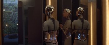 Movie still from “Ex Machina” (2014), directed by Alex Garland – A woman is standing in front of a mirror and looking in the mirror; Medium shot, Over the shoulder angle