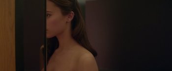 Movie still from “Ex Machina” (2014), directed by Alex Garland – A woman with long brown hair is standing in front of a mirror; Close Up shot, Over the shoulder angle