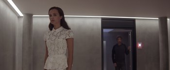 Movie still from “Ex Machina” (2014), directed by Alex Garland – A woman in a white dress standing in front of a man; Medium shot, Low angle
