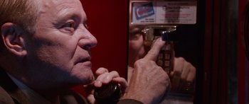 Movie still from “Glengarry Glen Ross” (1992), directed by James Foley – An older man holding a bottle of soda and a cell phone in front of him; Close Up shot, Low angle