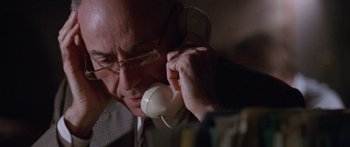 Movie still from “Glengarry Glen Ross” (1992), directed by James Foley – An older man talking on a phone while wearing glasses; Close Up shot, Low angle