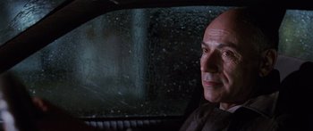 Movie still from “Glengarry Glen Ross” (1992), directed by James Foley – An older man sitting in the back seat of a car; Close Up shot, Low angle