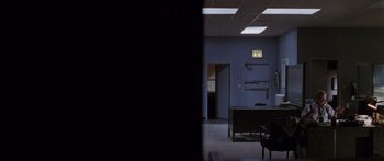 Movie still from “Glengarry Glen Ross” (1992), directed by James Foley – An empty room with a desk and chairs in it; Wide shot, High angle