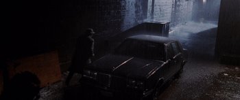 Movie still from “Glengarry Glen Ross” (1992), directed by James Foley – A man walking next to a car in the dark; Wide shot, High angle