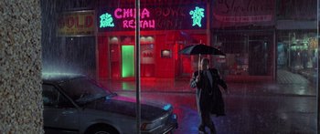 Movie still from “Glengarry Glen Ross” (1992), directed by James Foley – A man holding an umbrella while standing in the rain; Wide shot, Low angle