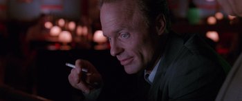 Movie still from “Glengarry Glen Ross” (1992), directed by James Foley – A man smoking a cigarette in a dark room; Close Up shot, Low angle