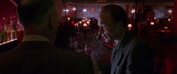 Movie still from “Glengarry Glen Ross” (1992), directed by James Foley – A man is smoking a cigarette in a bar; Medium shot, Over the shoulder angle
