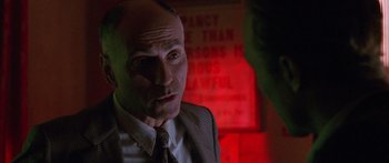 Movie still from “Glengarry Glen Ross” (1992), directed by James Foley – A man in a suit and tie in front of a red wall; Close Up shot, Low angle