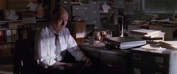 Movie still from “Glengarry Glen Ross” (1992), directed by James Foley – An older man sitting at a desk in front of a filing cabinet; Medium shot, Low angle