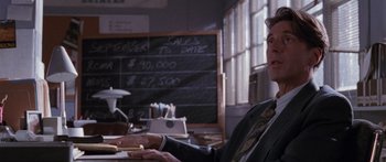 Movie still from “Glengarry Glen Ross” (1992), directed by James Foley – A man sitting in front of a chalkboard; Medium shot, Over the shoulder angle