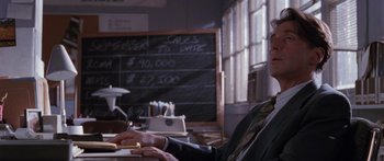 Movie still from “Glengarry Glen Ross” (1992), directed by James Foley – A man sitting in front of a blackboard using a computer; Close Up shot, Over the shoulder angle