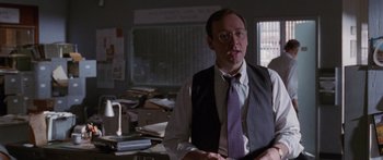 Movie still from “Glengarry Glen Ross” (1992), directed by James Foley – A man in a suit and purple tie in a room; Medium shot, Over the shoulder angle