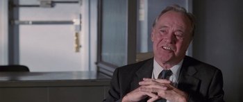 Movie still from “Glengarry Glen Ross” (1992), directed by James Foley – An older man wearing a suit and tie talking; Close Up shot, Over the shoulder angle