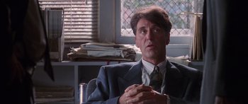 Movie still from “Glengarry Glen Ross” (1992), directed by James Foley – A man wearing a suit and tie sitting in front of a window; Close Up shot, Low angle