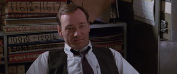 Movie still from “Glengarry Glen Ross” (1992), directed by James Foley – Kevin spacey in a suit and tie in front of a bookshelf; Close Up shot, High angle