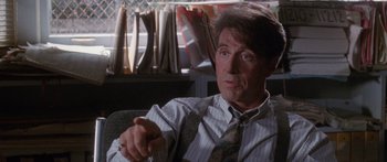Movie still from “Glengarry Glen Ross” (1992), directed by James Foley – A person sitting in a chair wearing a tie; Close Up shot, Over the shoulder angle
