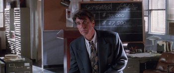 Movie still from “Glengarry Glen Ross” (1992), directed by James Foley – A man wearing a suit and tie standing in front of a chalkboard; Close Up shot, Over the shoulder angle