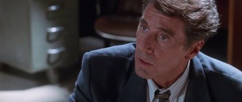 Movie still from “Glengarry Glen Ross” (1992), directed by James Foley – A man in a suit and tie sitting in a chair; Close Up shot, Over the shoulder angle