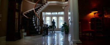Movie still from “Father Figures” (2017), directed by Lawrence Sher – A person standing in a large room with a spiral staircase; Wide shot, Low angle