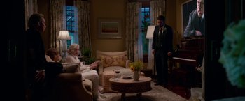 Movie still from “Father Figures” (2017), directed by Lawrence Sher – A man and a woman sitting in a living room next to each other; Wide shot, High angle