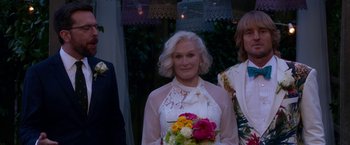 Movie still from “Father Figures” (2017), directed by Lawrence Sher – A woman in a white dress holding a bouquet of flowers; Medium shot, Over the shoulder angle