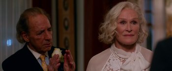 Movie still from “Father Figures” (2017), directed by Lawrence Sher – A woman in a white dress clapping her hands in front of another woman; Close Up shot, Over the shoulder angle