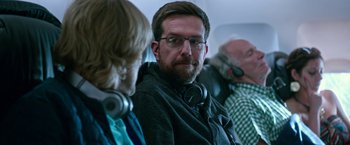 Movie still from “Father Figures” (2017), directed by Lawrence Sher – A man with a beard and glasses is listening to headphones; Close Up shot, Over the shoulder angle