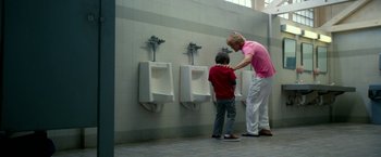 Movie still from “Father Figures” (2017), directed by Lawrence Sher – A man and a boy standing in front of urinals in a bathroom; Wide shot, Low angle